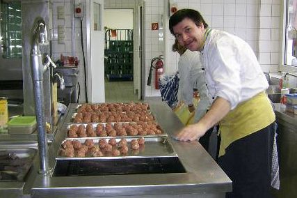 Ehrenamt in der Verpflegung Ein Helfer steht in einer Großküche und bereitet Fleischbällchen zu.