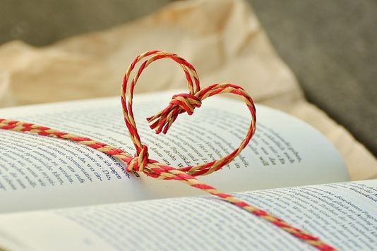 Aufgeschlagenes Buch mit einer Kordel, die ein Herz über den Seiten bildet.