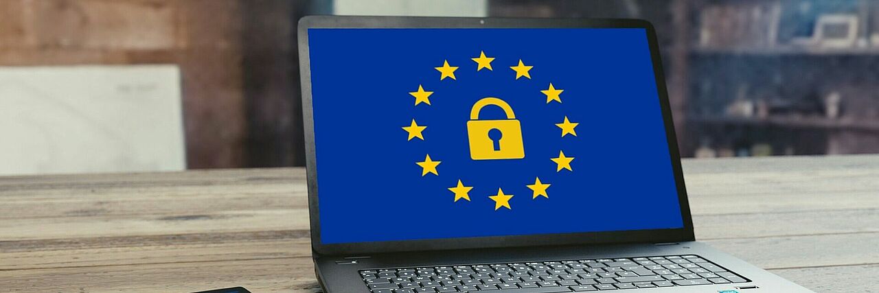 Ein Notebook auf dessen Bildschirm die Europaflagge mit einem gelben Vorhängeschloss in der Mitte