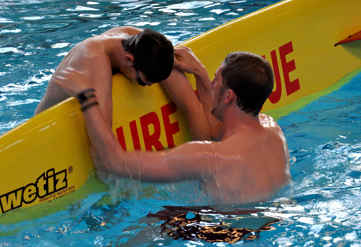 Ein Rettungsschwimmer in Ausbildung: Eine Person wird auf ein Rettungsbrett gerettet.