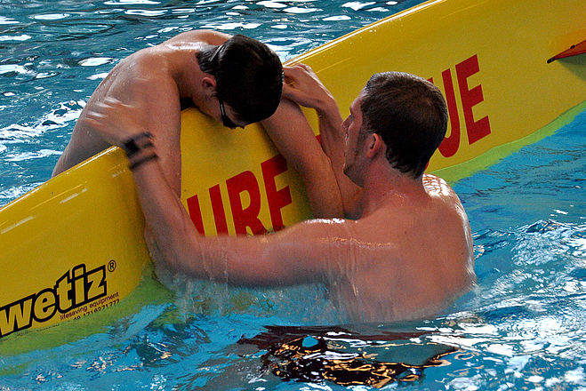 Ein Rettungsschwimmer in Ausbildung: Eine Person wird auf ein Rettungsbrett gerettet.