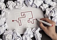 In mitten von Papiermüll wir eine Karte aufgedeckt in der in Rot ein Weg gezeichnet wird.