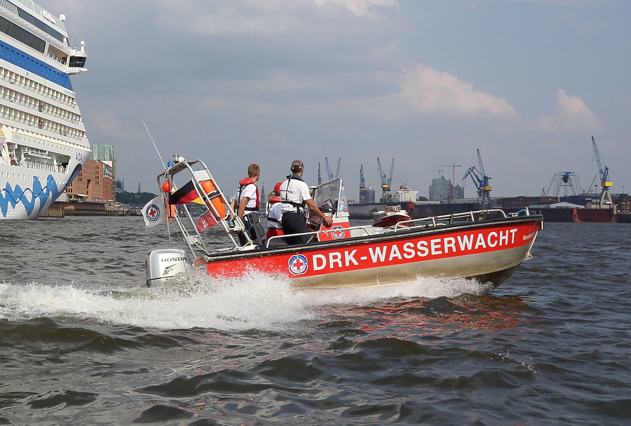 Material der Wasserwacht Unser Rettungsboot Woodstock III auf der Elbe, vor der Aida prima im Hamburger Hafen.